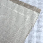 Ein Gebetsteppich mit glänzender Struktur in der Farbe crema